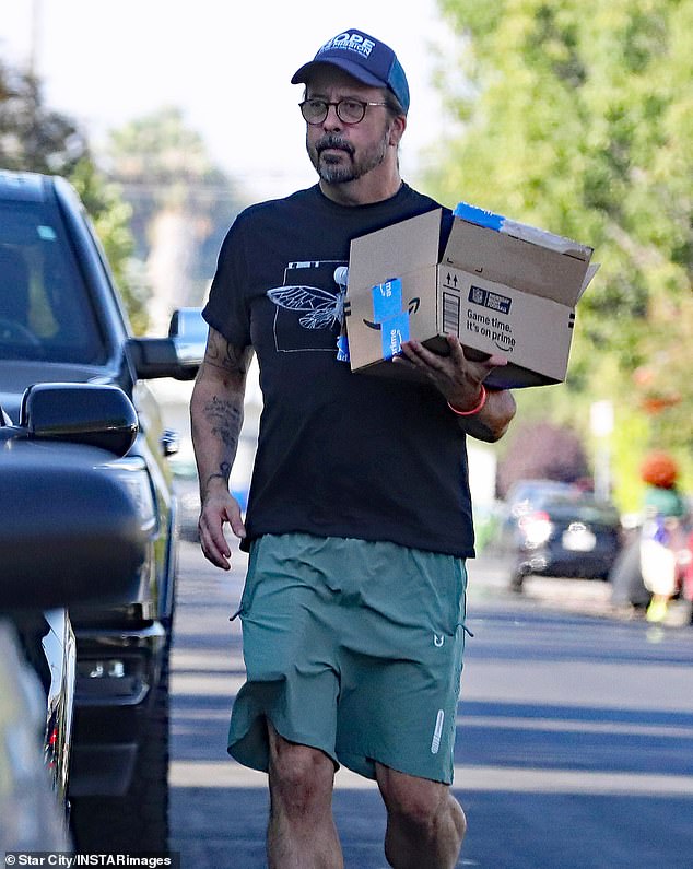 The Foo Fighters frontman, 55, whose latest effort to win back wife Jordyn Blum was recently revealed, looked somber as he carried an Amazon box to a house on a quiet, tree-lined street.