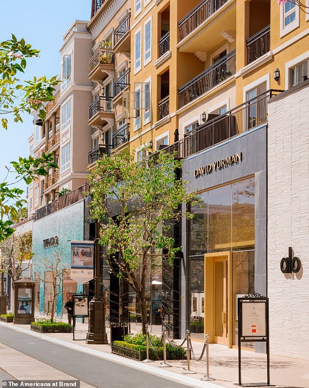 The apartments with balconies are located above the many shops.