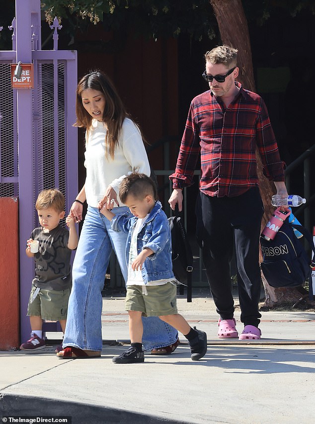 Culkin rocked a red plaid shirt and sweatshirts paired with pink Crocs. She carried her children's personalized backpacks and water bottles.