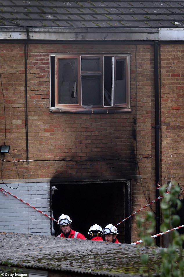 Firefighters inspect the rear of a fire that killed Dr. Shakoor's wife and children on October 15, 2012.