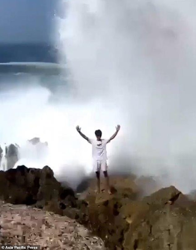 His friend posed with his arms raised, unaware of the incident unfolding behind him.