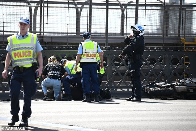 Police later arrested a motorcyclist who allegedly broke the roadblock and drove through the crash site (pictured).