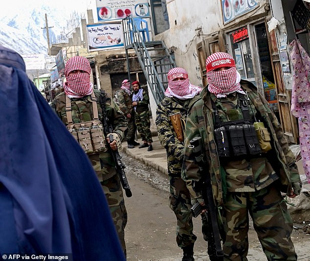 The alleged massacre comes after an offensive by the Iranian regime against migrants trying to escape the clutches of the Taliban. Pictured: Taliban security personnel stand guard as a burqa-clad Afghan woman (right) walks down a street in a market in the Baharak district of Badakhshan province on February 26, 2024.