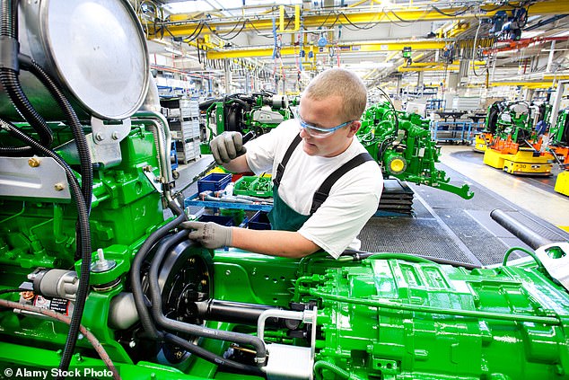 John Deere personnel work on agricultural equipment. The company lays off workers