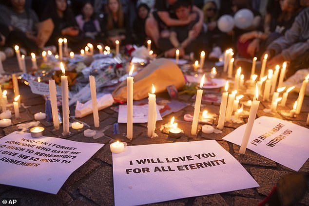 Candles are placed on the pavement as fans of former One Direction singer Liam Payne gather to honor him.