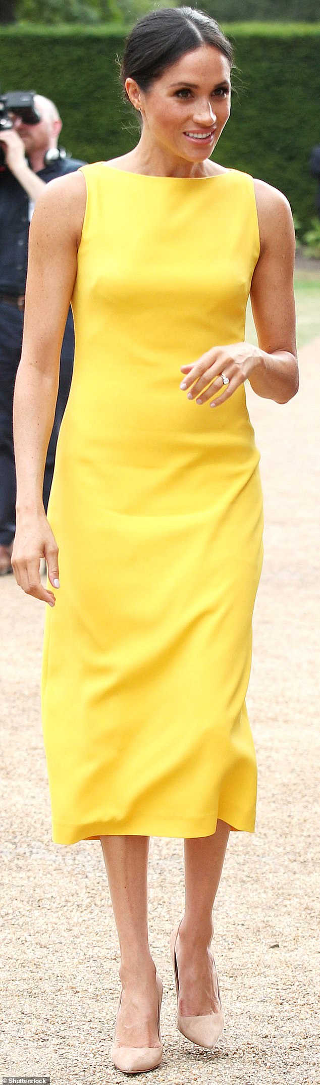 Meghan is wearing a simple Brandon Maxwell shirt in a sunny color and closed-toe Manolo shoes