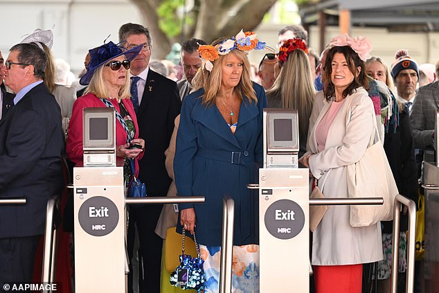 A group of women with headdresses and winter jackets over their dresses waited patiently at the turnstiles.