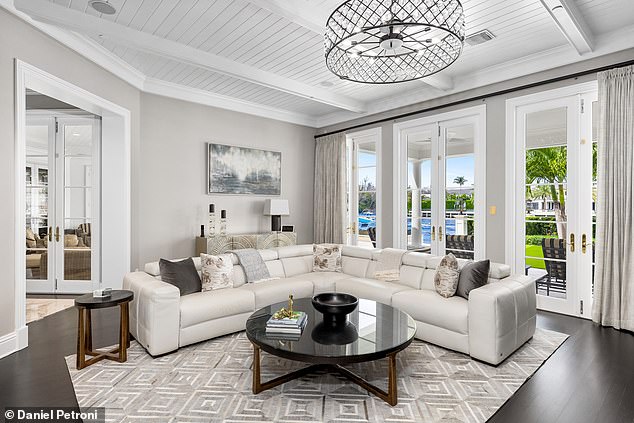 Plush seating and large windows bathe this living room space in natural light. It is an ideal place to relax or just for an informal conversation.