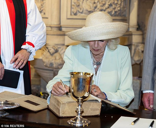 Queen Camilla signs a Bible and book of common prayer while attending Church