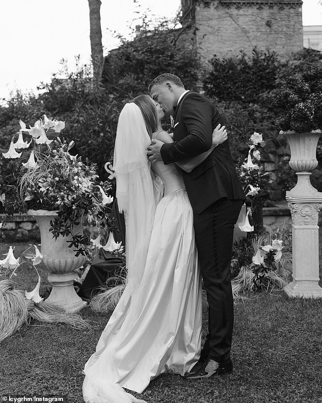 The couple looked deeply in love in a black and white frame that saw them kiss passionately in a garden surrounded by ornate flower arrangements.