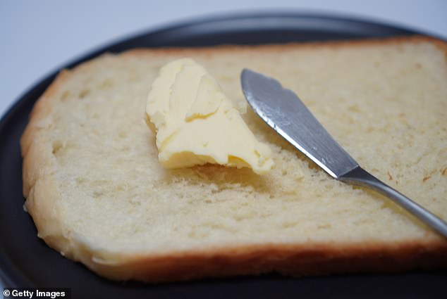 Cut a small piece of bread and spread it with butter on your plate, never do it at the table.