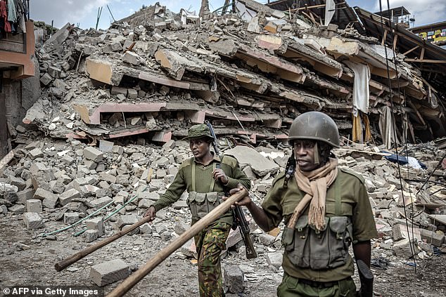 Kenyan police officers instruct passersby to evacuate area next to collapsed residential building