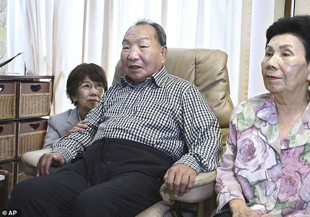 Iwao Hakamada, center, sits with his sister, right, as Tsuda arrives home to apologize.