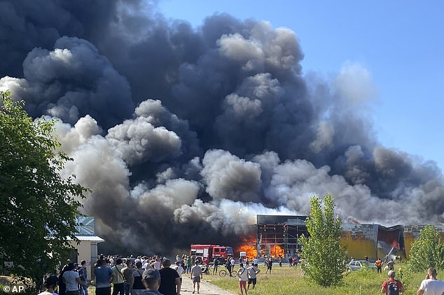 Onlookers gather as the shopping center is engulfed in flames shortly after being hit by two Russian guided missiles.