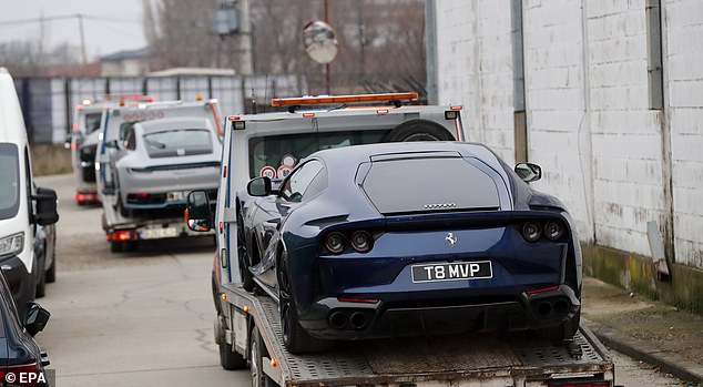 A Ferrari sports car belonging to Andrew Tate is removed from his property on a transport platform by Romanian law enforcement officers in January 2023.