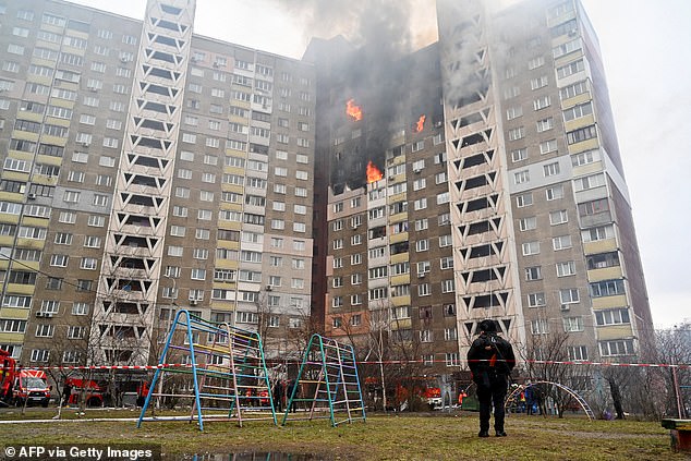 A law enforcement officer stands next to a residential building damaged as a result of a missile attack in kyiv on February 7, 2024.