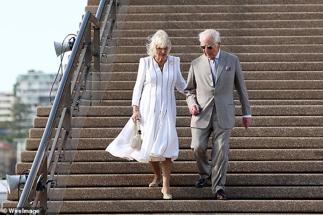 Queen Camilla and King Charles walk down the steps of the Sydney Opera House.