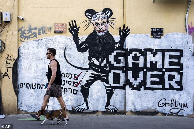 People walk past freshly painted graffiti depicting Hamas leader Yahya Sinwar, days after he was killed by Israeli forces in Gaza, in Tel Aviv, Israel, Sunday, October 20, 2024.