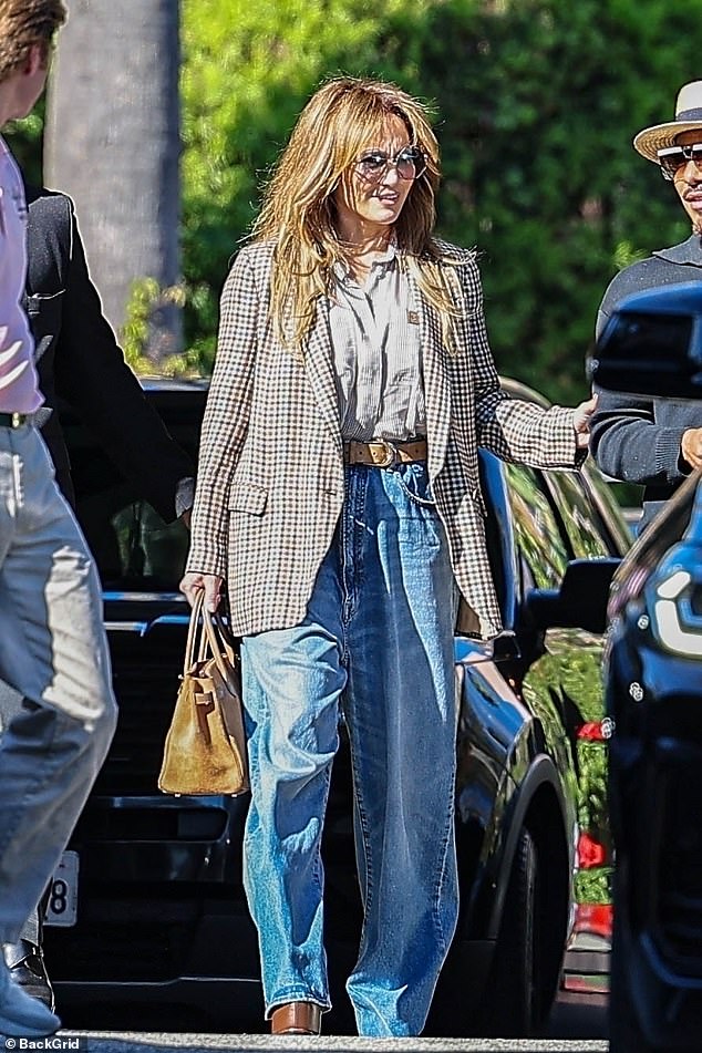 The Hustlers star rocked a stylish blazer over a striped button-down tucked into a pair of oversized blue jeans.