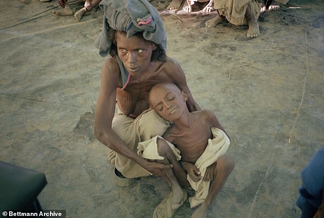 At the Mile feeding station, amid famine in Ethiopia, a mother holds her child while waiting for food, March 12, 1984.