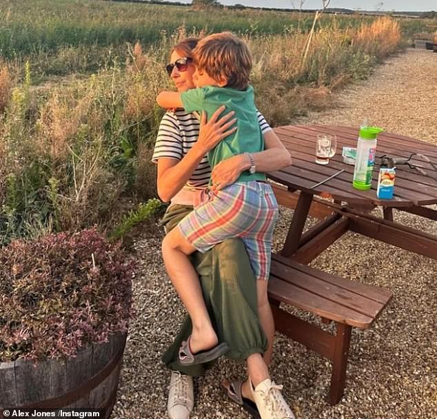 In the family album, Alex shared a cute photo of her holding her son Teddy, 7, on her lap while sitting on a picnic bench watching the sunset.