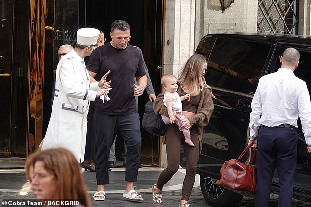 She finished her look with a pair of khaki sneakers and statement sunglasses while resting her daughter Robbie on her hip.