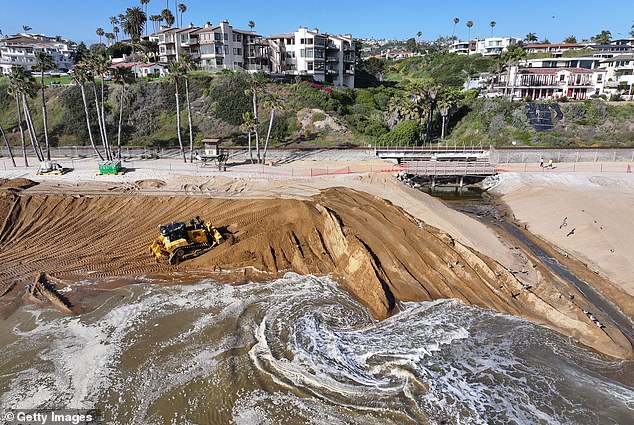 An excavator moves freshly delivered sand to a public beach in San Clemente as part of a sand replenishment project.