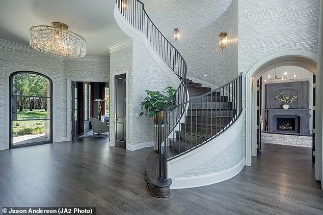 Near the main entrance is a spiral staircase bordered by a railing, while an ornate chandelier can be seen nearby.