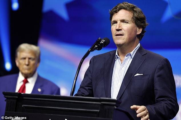 Political commentator Tucker Carlson speaks alongside Republican presidential candidate, former US President Donald Trump, during a Turning Point Action campaign rally.