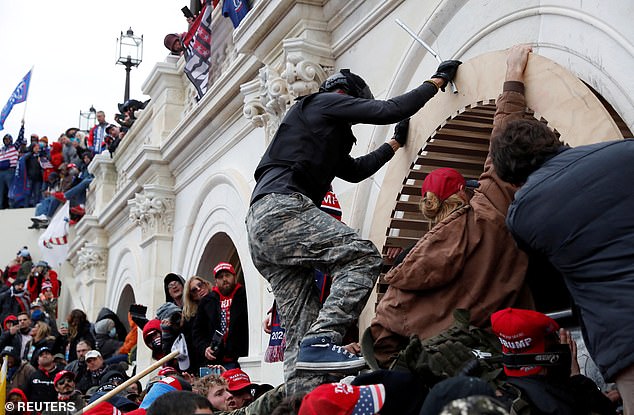 Pro-Trump protesters scale a wall as they storm the US Capitol building on January 6, 2021