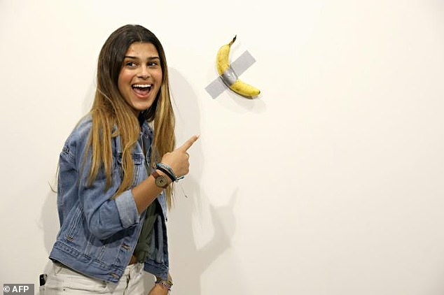 A woman poses with Cattelan's work before it was eaten.