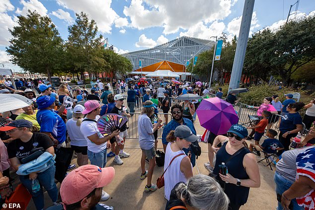 Harris supporters holding fans and umbrellas as they wait in the sun to attend the vice president's rally in Houston on October 25.