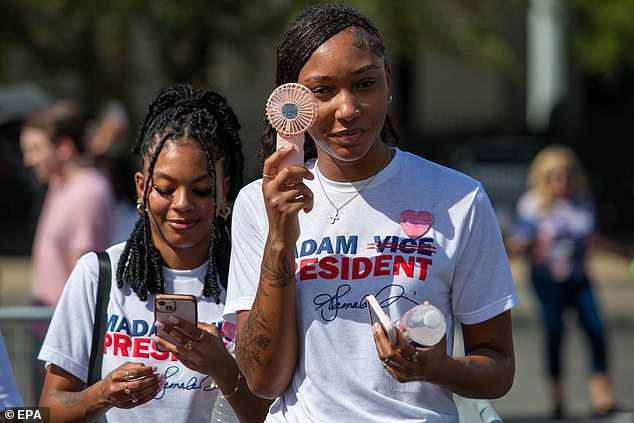 A Harris supporter holds a fan while waiting for the vice president's rally in Houston.