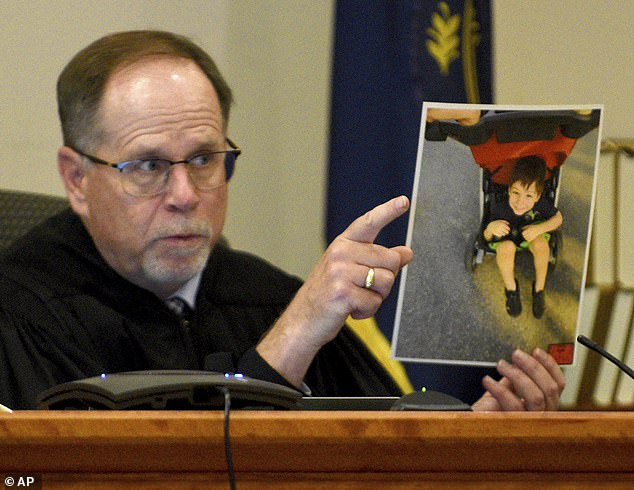 Superior Court Judge Charles Temple holds a photograph of Elijah Lewis as he explains his sentence at the hearing for Danielle Dauphinais in Hillsborough County Superior Court South in Nashua, New Hampshire, on Friday.