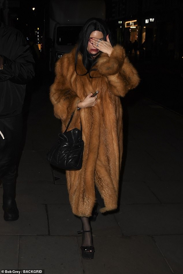 She covered herself from the cold with a burnt orange faux fur coat and carried her essentials in a black quilted bag.