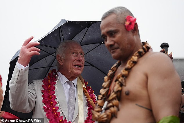 King Charles III points out the rain during a farewell ceremony at Siumu Village on the final day of the royal visit to Australia and Samoa.