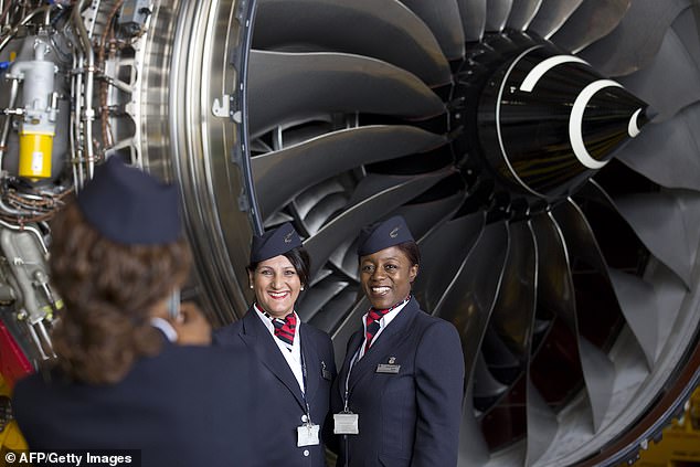 Airline staff pose for a photo in front of a Rolls Royce Trent 1000 turbofan engine at an event to mark the arrival of a British Airways Airbus A380 at London Heathrow Airport on July 4, 2013.