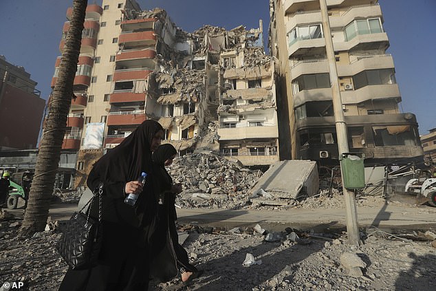 Lebanese women walk past a building destroyed by an Israeli airstrike in Tyre, Lebanon, Monday, October 28, 2024.