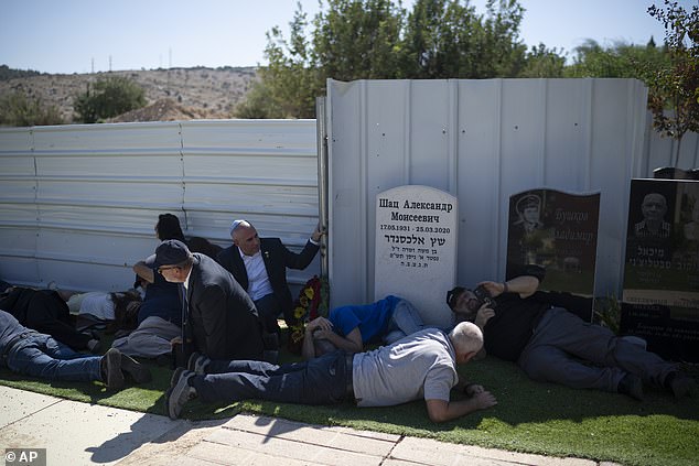 People take cover as a siren warns of incoming rockets during the funeral of Alexei Popov, who was killed during a rocket attack launched from Lebanon last weekend, at the Tel Regev cemetery on the outskirts of Haifa , northern Israel, on Monday, October 21. 2024