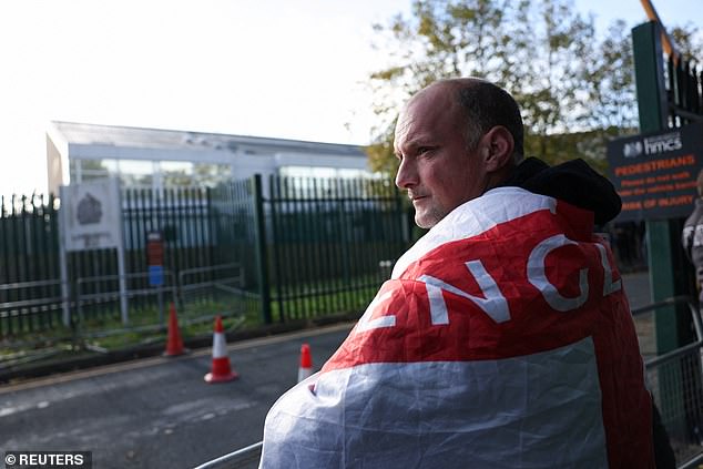 A man carrying an English flag watches as Robinson's supporters gather outside Woolwich Crown Court.