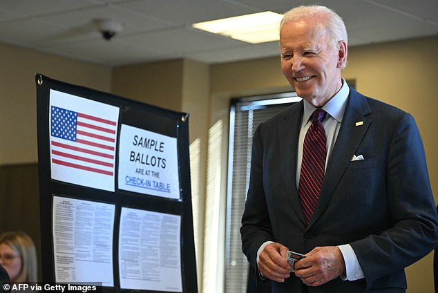 Biden, 81, smiles with his license in hand as he waits to vote alongside other Delaware residents.