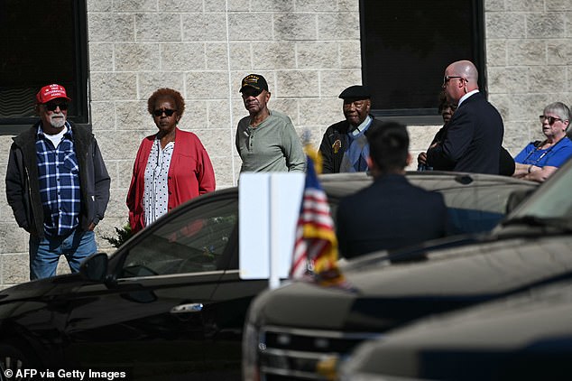 The 81-year-old president walked past a voter (left) wearing a MAGA cap with the message 