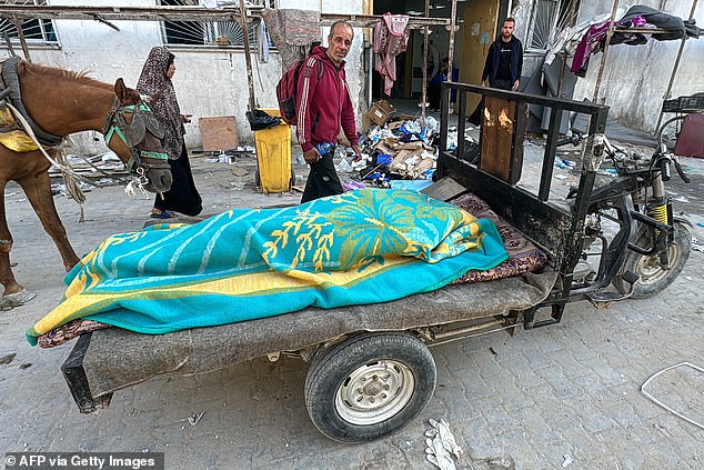 A body lies covered by a blanket on a cart in front of the Kamal Adwan hospital in Beit Lahia, northern Gaza Strip, on October 28, 2024.