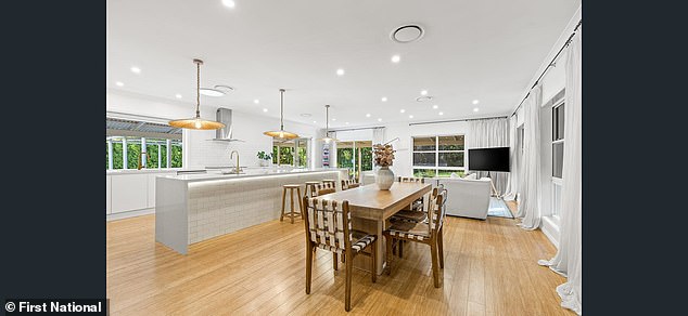 A sleek, modern kitchen includes a pantry, induction cooktop, stone countertops, and a large, spacious island.