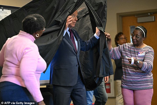 US President Joe Biden draws back the black curtain surrounding the polls after casting his vote on Monday.