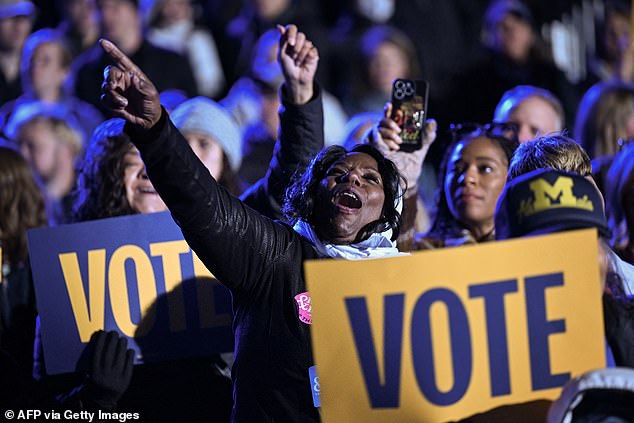 Supporters cheer for Harris and hold signs saying 