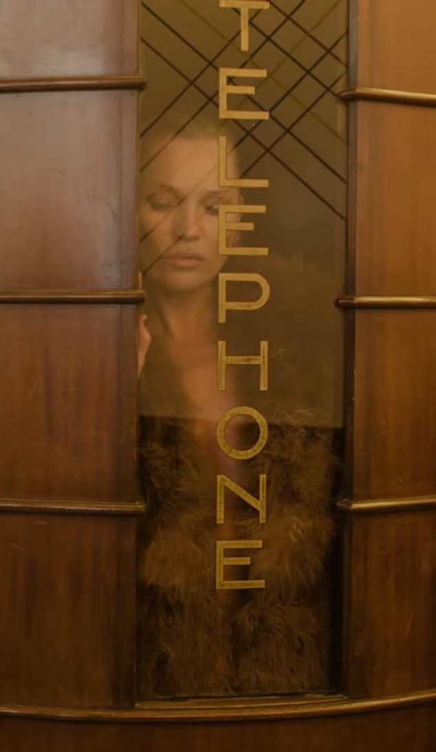 Kate is seen through the fogged-up window of a hotel phone booth in a scene from the advertisement.