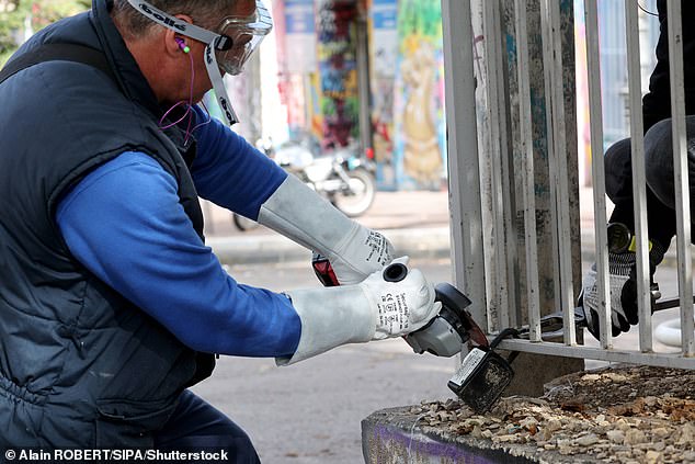 A worker in Marseille is seen cutting a safe from a railing on October 28.