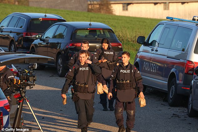 Law enforcement officers walk past gathered media during the chase on October 28, 2024 near Rohrbach, Austria.