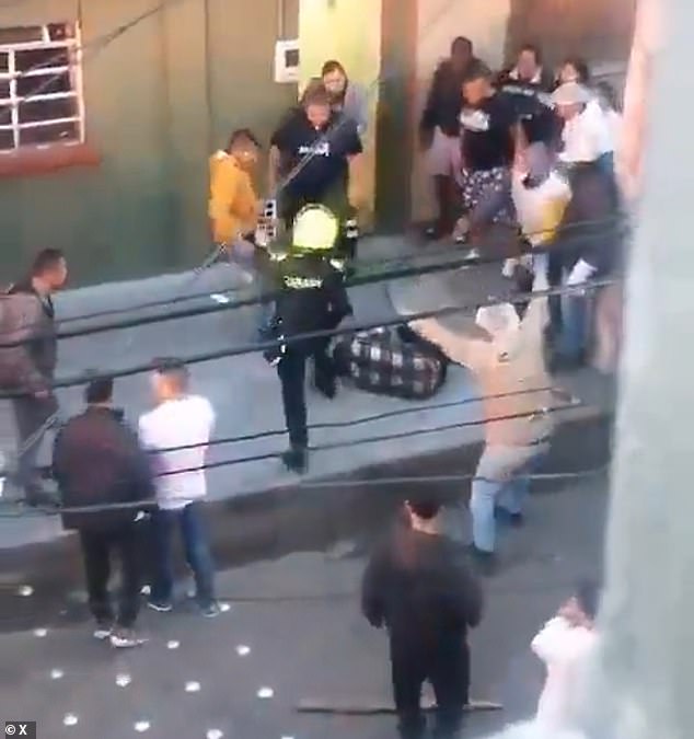 A police officer is seen intervening after neighbors dragged Darwin Beltrán out of his house and beat him when they found out about the attacks.